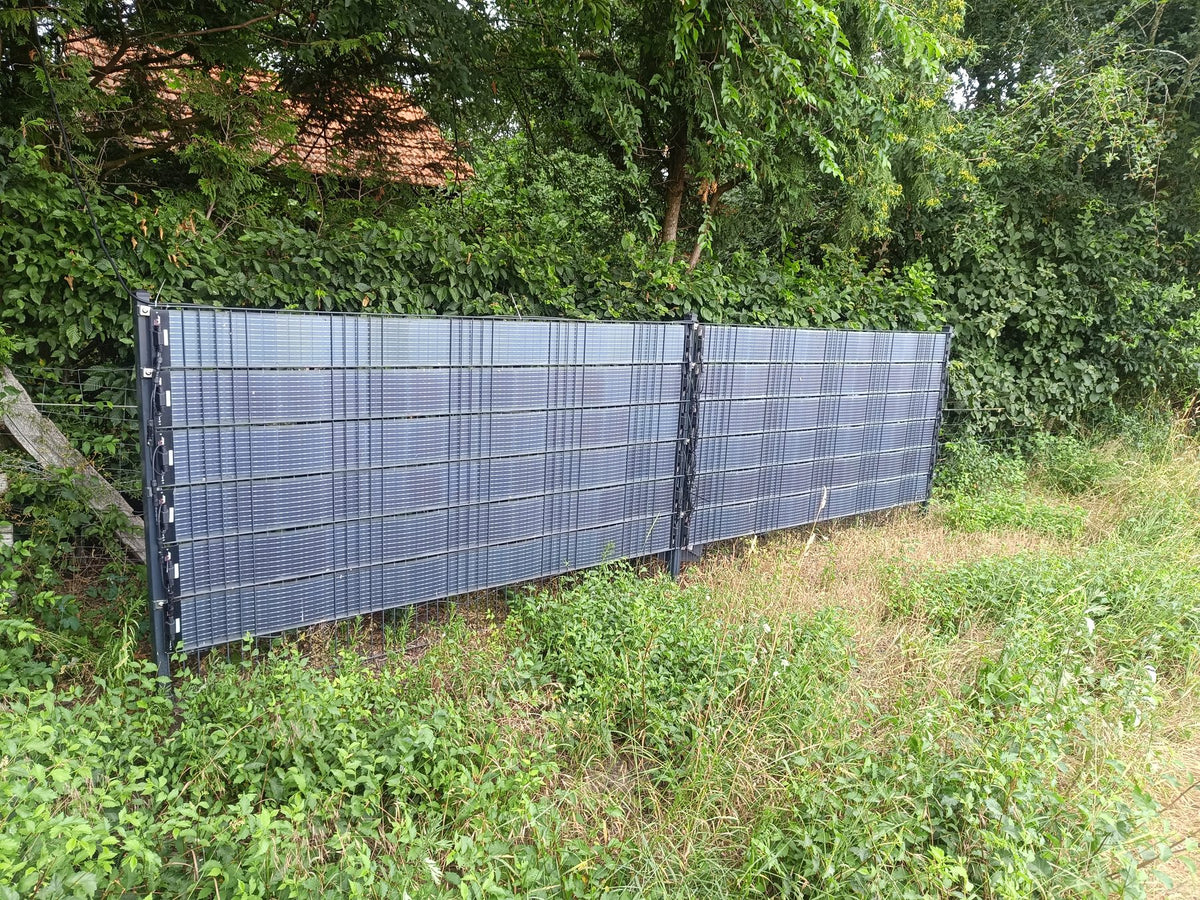 Sunbooster VERTICAL+ Solarzaun vor einer Hecke