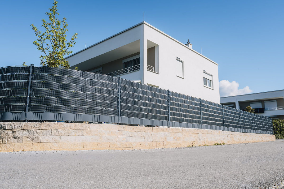 Sunbooster VERTICAL+ Solarzaun auf einer Mauer vor einem modernen Einfamilienhaus