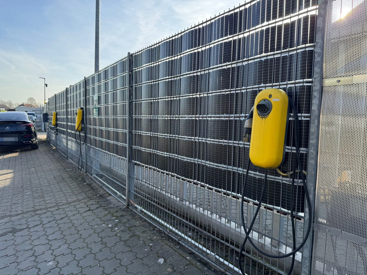 Sunbooster VERTICAL+ Solarzaun an einem Firmenparkplatz mit Ladestationen